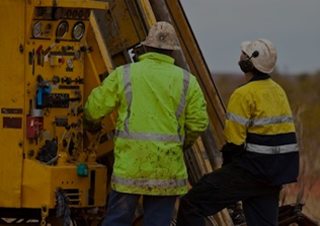 An image of two employees investigating machinery outdoors