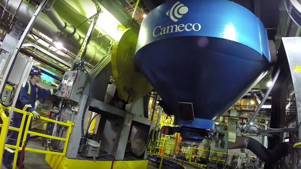 An image of a cameco branded piece of equipment with an employee nearby, in a facility